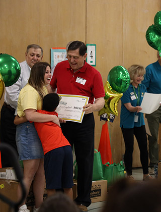  Teacher surprised with a check and then a hug from a student.